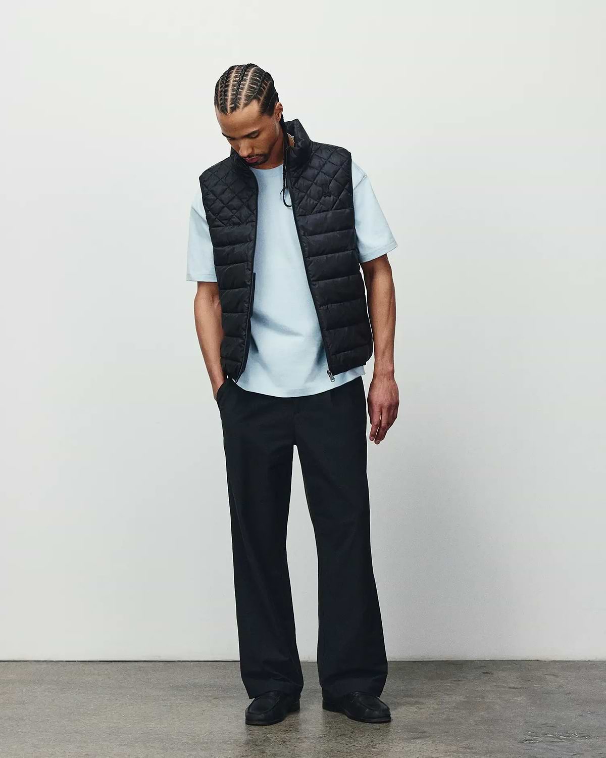 Mens Emerik Puffer Vest in black with a quilted design, paired with a light blue classic fit jersey t-shirt and relaxed black pants, showcasing refined streetwear.