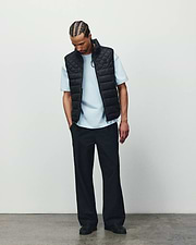 Mens Emerik Puffer Vest in black with a quilted design, paired with a light blue classic fit jersey t-shirt and relaxed black pants, showcasing refined streetwear.
