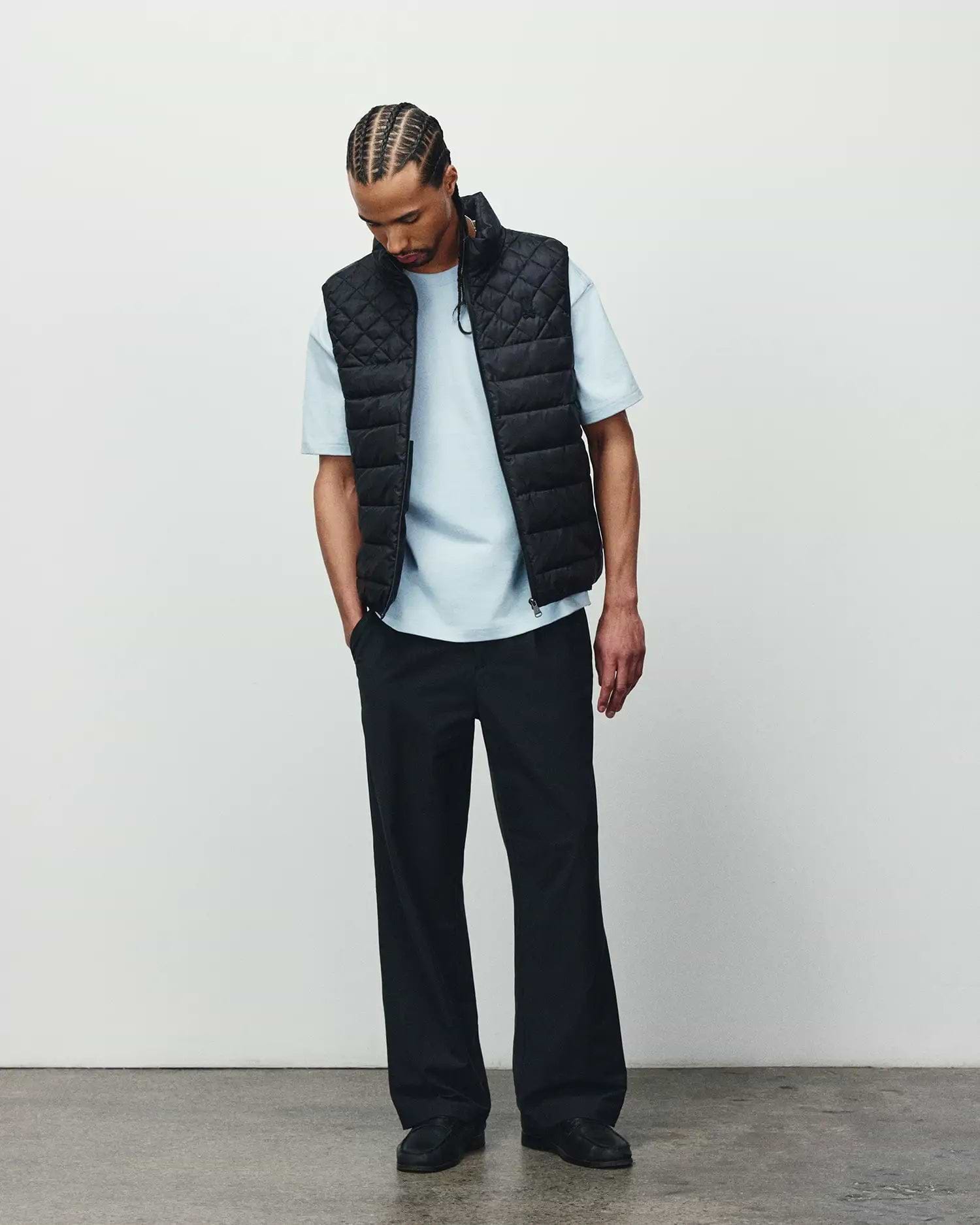 Mens Emerik Puffer Vest in black with a quilted design, paired with a light blue classic fit jersey t-shirt and relaxed black pants, showcasing refined streetwear.