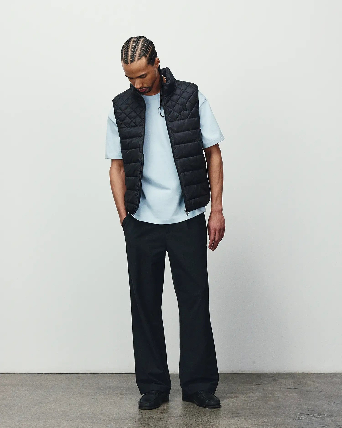 Mens Emerik Puffer Vest in black with a quilted design, paired with a light blue classic fit jersey t-shirt and relaxed black pants, showcasing refined streetwear.