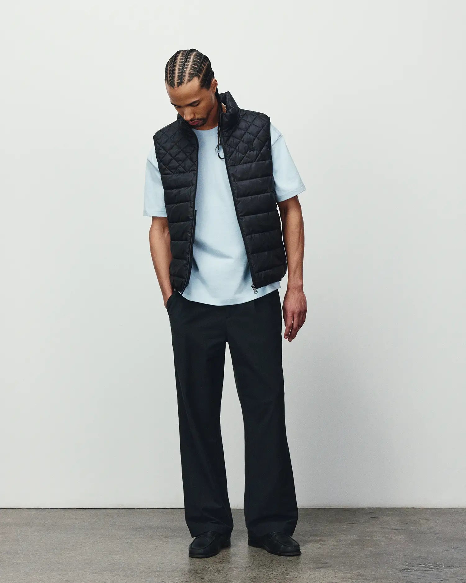 Mens Emerik Puffer Vest in black with a quilted design, paired with a light blue classic fit jersey t-shirt and relaxed black pants, showcasing refined streetwear.