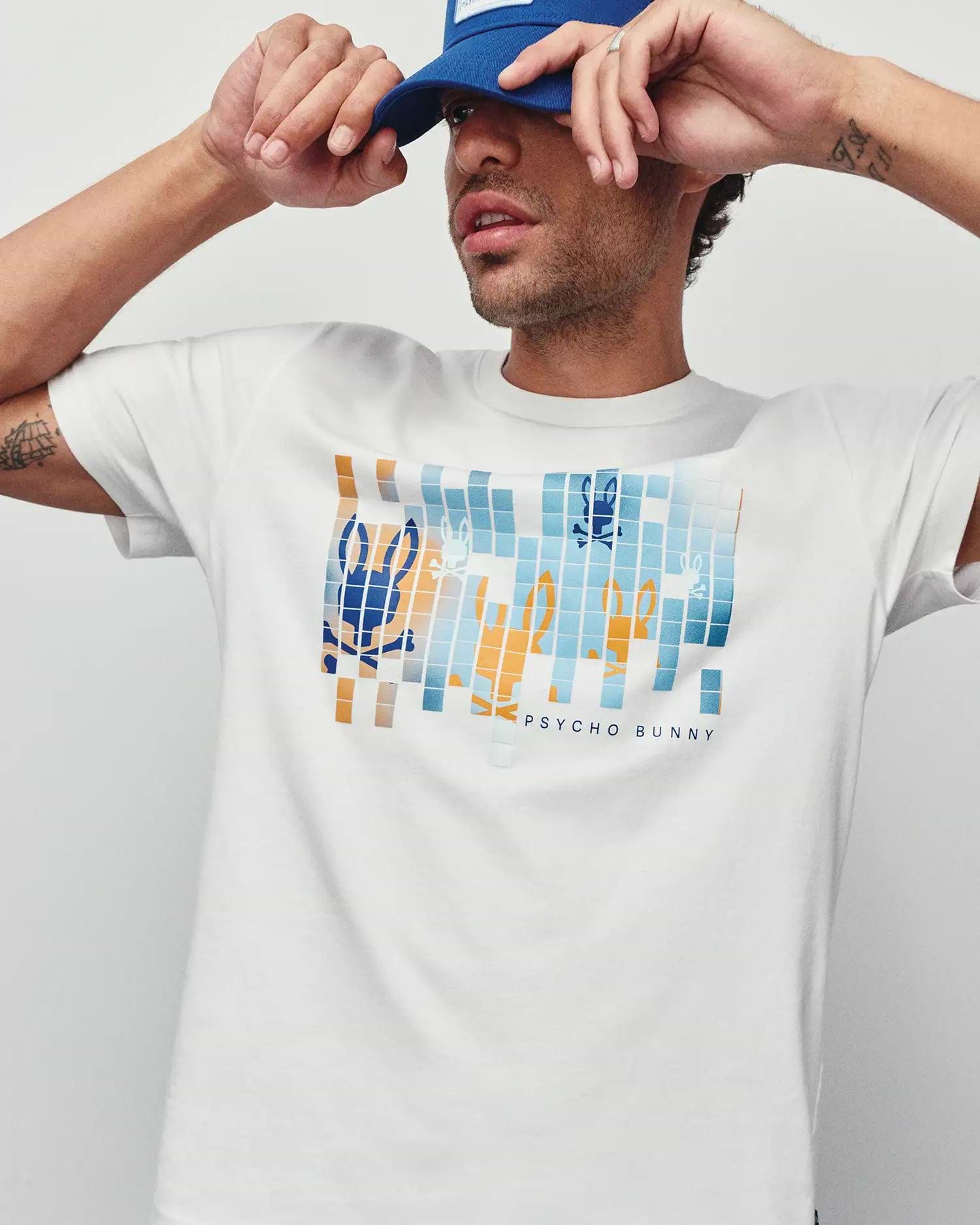 Mens Zander Graphic Tee, white classic fit jersey t-shirt featuring a large pixelated blue and orange Psycho Bunny skull logo graphic on the chest with Psycho Bunny text.