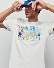 Mens Zander Graphic Tee, white classic fit jersey t-shirt featuring a large pixelated blue and orange Psycho Bunny skull logo graphic on the chest with Psycho Bunny text.