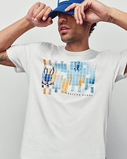 Mens Zander Graphic Tee, white classic fit jersey t-shirt featuring a large pixelated blue and orange Psycho Bunny skull logo graphic on the chest with Psycho Bunny text.