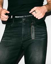 Black Mens Ace Knit Denim Pant, slim fit, with a subtle distressed texture and an attached brown leather Psycho Bunny embossed keychain. Black ribbed undershirt and black Psycho Bunny logo waistband underwear.