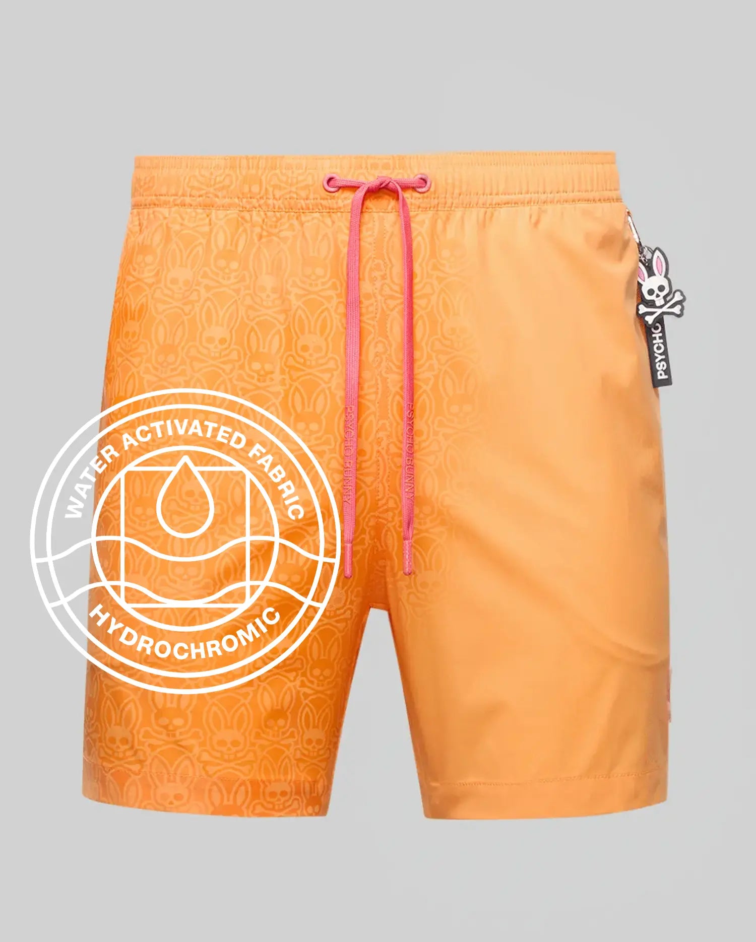 Mens Samos Hydrochromic Printed Swim Trunk, vibrant orange with a subtle water-activated bunny skull pattern, pink Psycho Bunny drawstrings, and a side logo tag.