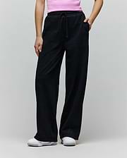 Womens Jules Lurex Sweatpant in black, featuring a relaxed wide-leg fit, shimmering lurex knit fabric, drawstring waist, and a small embroidered Psycho Bunny skull logo near the right pocket.