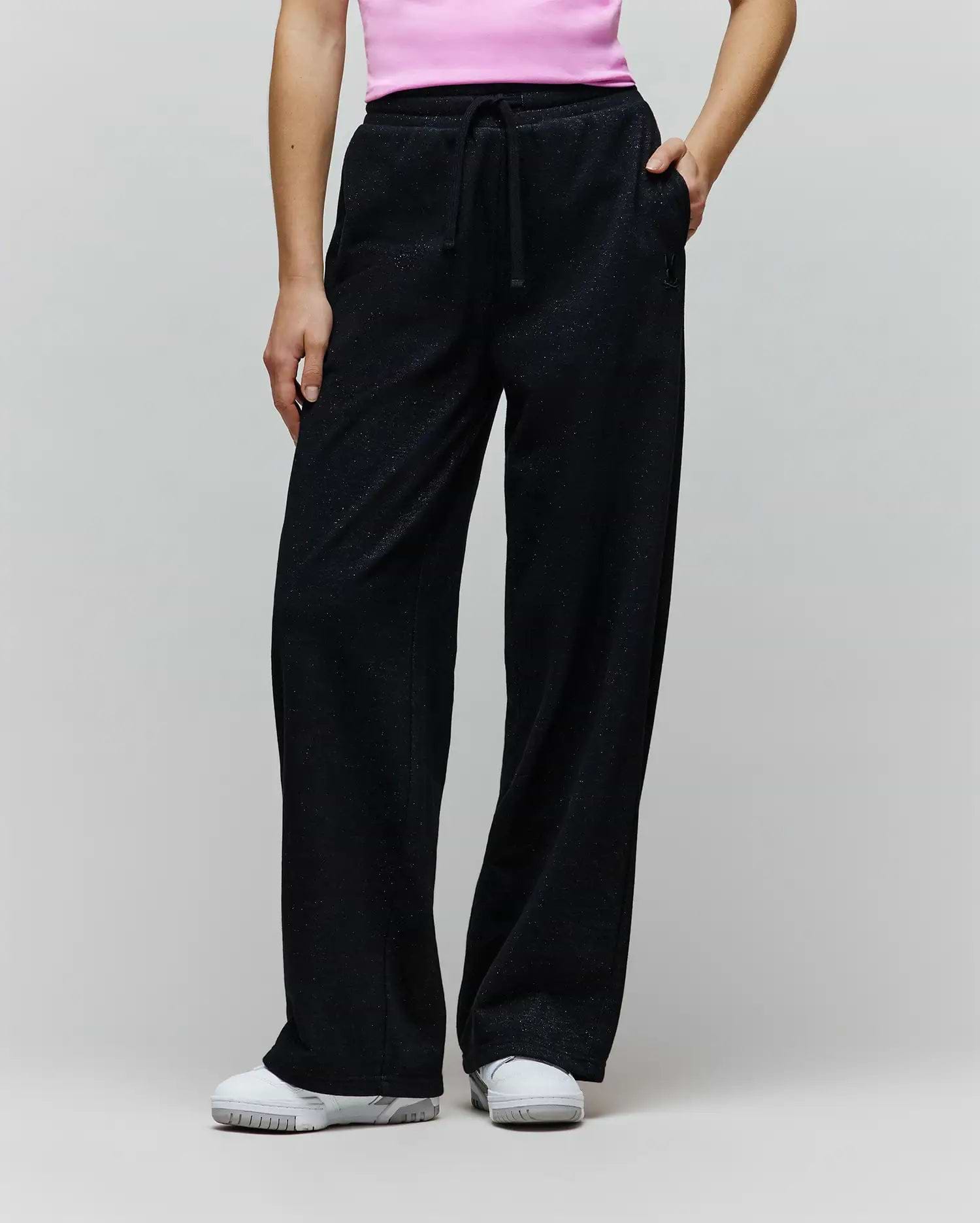 Womens Jules Lurex Sweatpant in black, featuring a relaxed wide-leg fit, shimmering lurex knit fabric, drawstring waist, and a small embroidered Psycho Bunny skull logo near the right pocket.