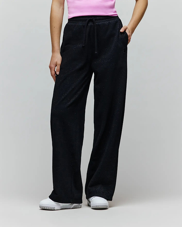 Womens Jules Lurex Sweatpant in black, featuring a relaxed wide-leg fit, shimmering lurex knit fabric, drawstring waist, and a small embroidered Psycho Bunny skull logo near the right pocket.