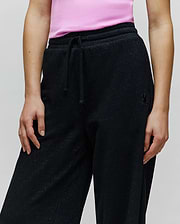 Womens Jules Lurex Sweatpant, black relaxed fit with subtle silver lurex sparkle, featuring a drawstring waist and a small tonal embroidered Psycho Bunny skull logo on the right hip.