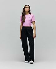 Pink cropped jersey t-shirt with a small embroidered Psycho Bunny skull logo on the left chest, paired with black Womens Jules Lurex Sweatpant featuring a relaxed wide-leg fit and subtle shimmer.