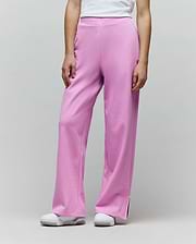 Womens Daisie Fleece Joggers in bright pink, with a relaxed wide-leg fit, soft fleece texture, small embroidered bunny skull logo on the left thigh, and white piped side leg slits.