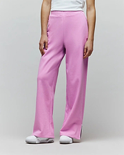 Womens Daisie Fleece Joggers in bright pink, with a relaxed wide-leg fit, soft fleece texture, small embroidered bunny skull logo on the left thigh, and white piped side leg slits.