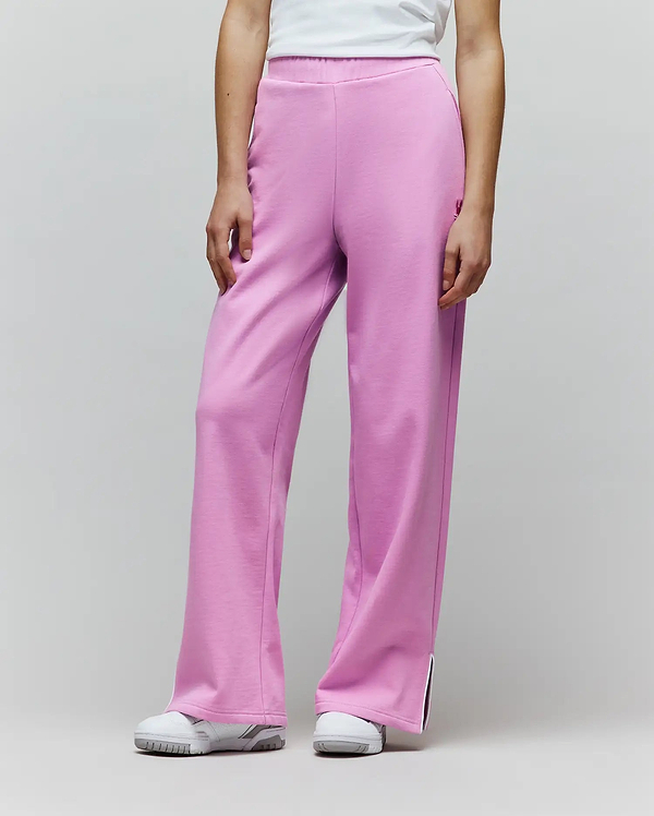 Womens Daisie Fleece Joggers in bright pink, with a relaxed wide-leg fit, soft fleece texture, small embroidered bunny skull logo on the left thigh, and white piped side leg slits.