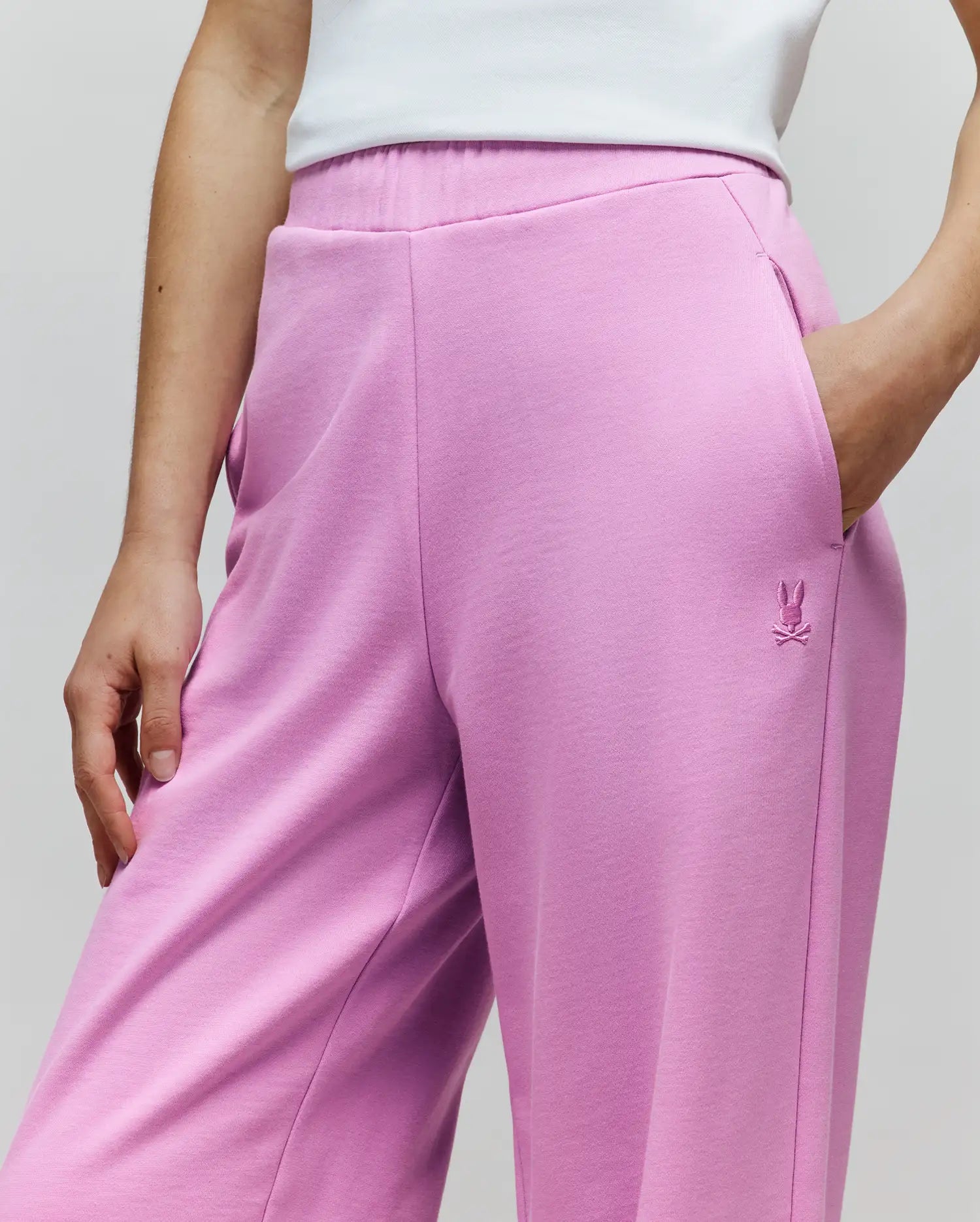 Womens Daisie Fleece Joggers in vibrant pink, featuring a relaxed fit, soft fleece fabric, and an elastic waistband. A small, tonal embroidered Psycho Bunny skull logo is on the upper right thigh.