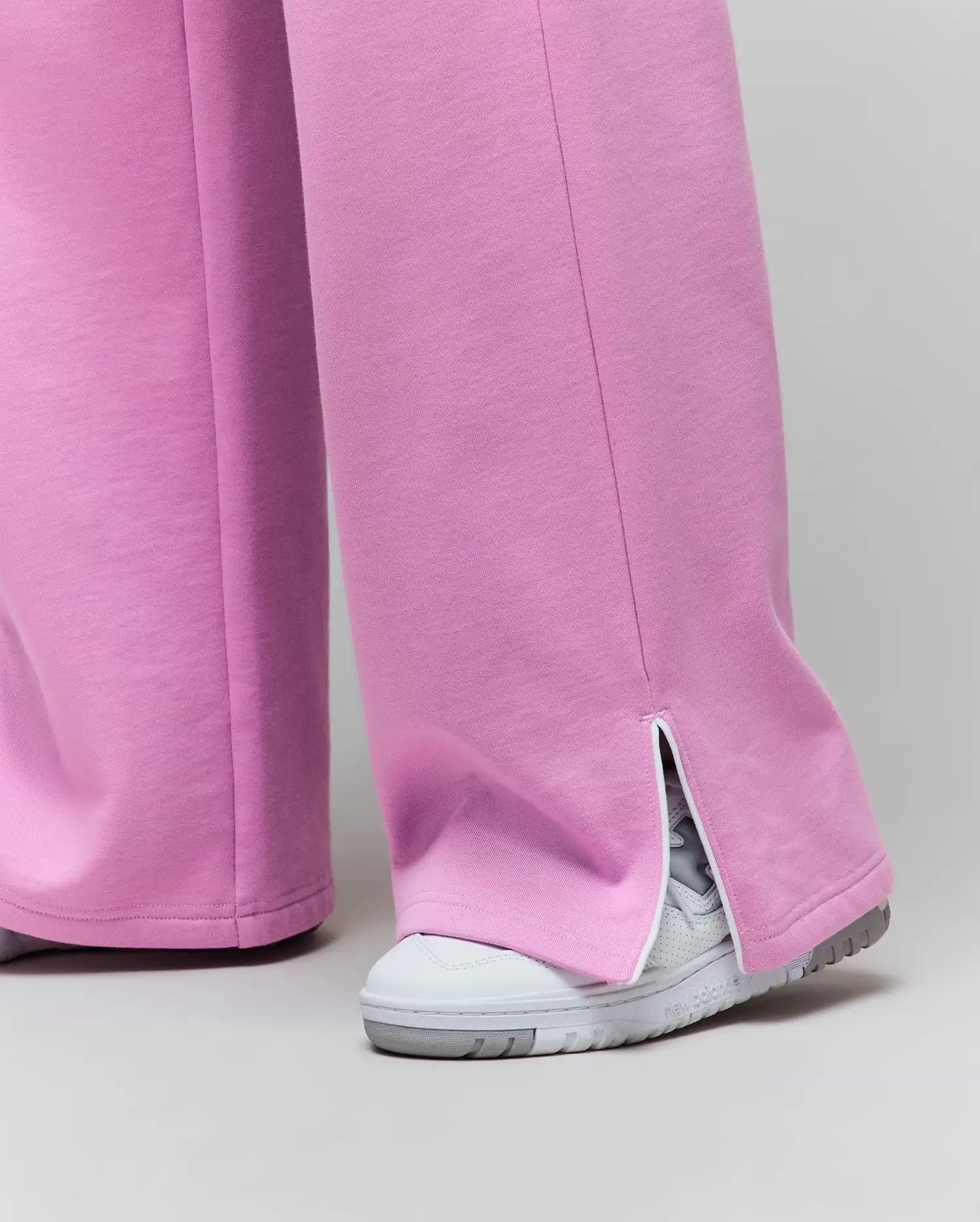 Womens Daisie Fleece Joggers, a relaxed wide-leg style in soft pink fleece jersey, featuring a distinctive ankle split hem with white trim.