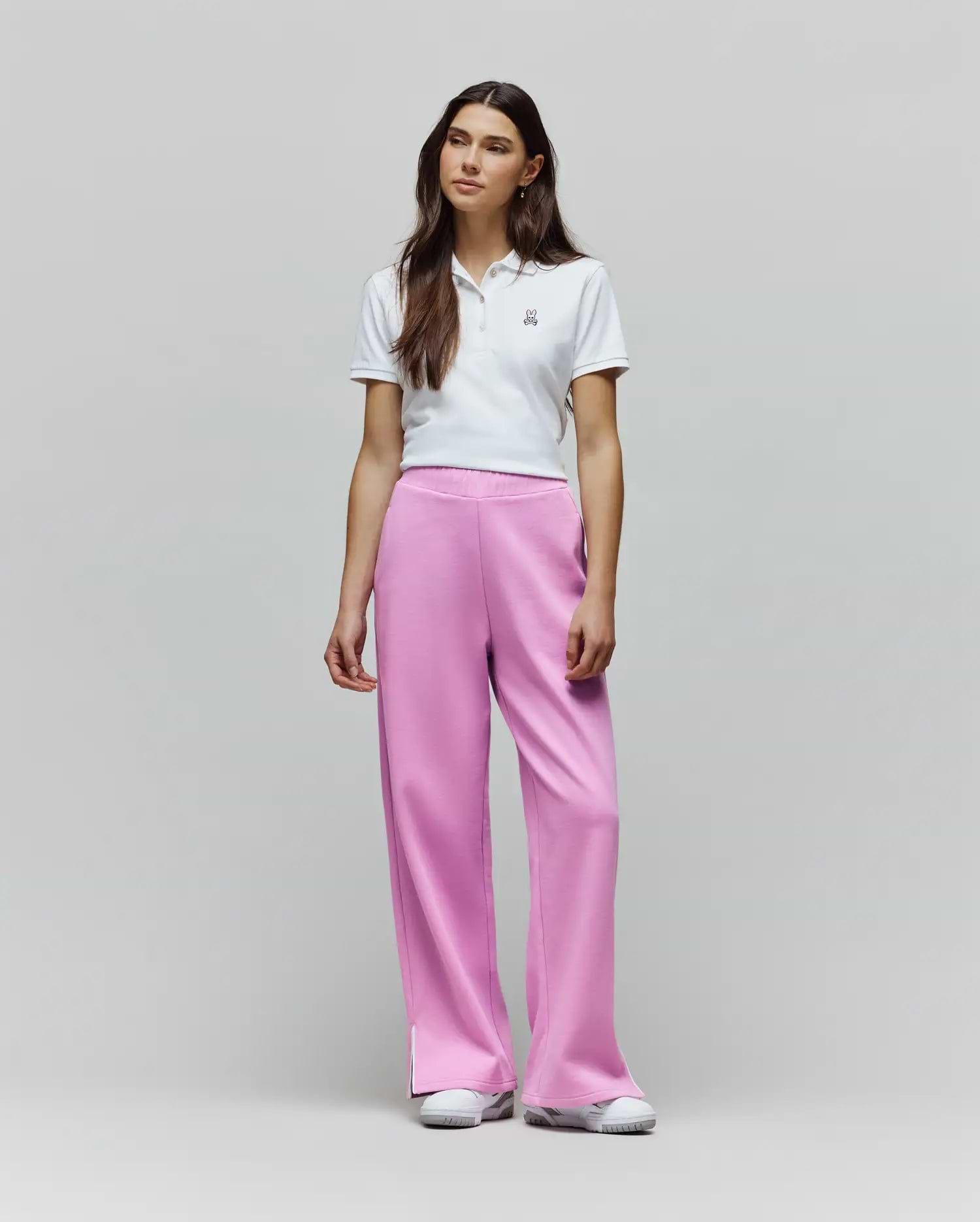 White cropped pique polo with embroidered Psycho Bunny logo, paired with Womens Daisie Fleece Joggers in vibrant pink, featuring a relaxed wide-leg fit and subtle side split detail.