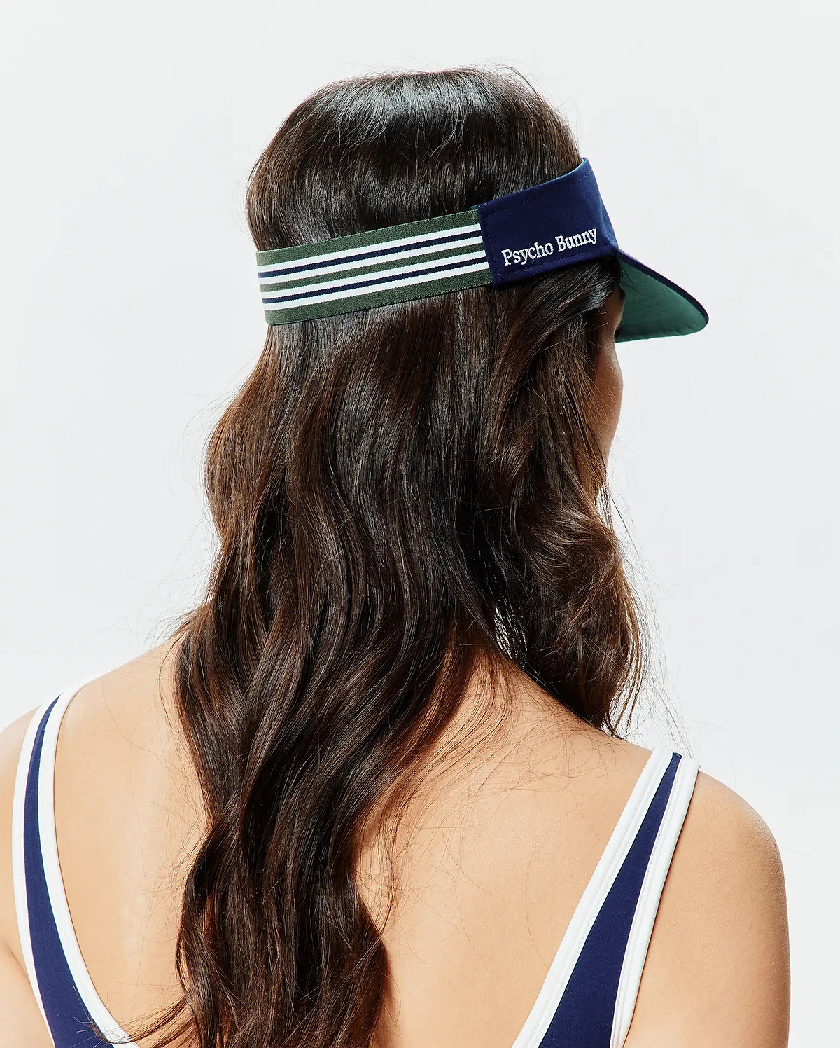 Women's Sport Visor in navy blue with a dark green underside brim, featuring a green, navy, and white striped elastic back strap and embroidered white Psycho Bunny text on the front. (3)