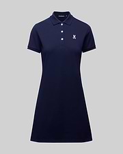 The WOMENS POLO DRESS - WO2000003 by Psycho Bunny is a navy blue, short-sleeve 100% Pima cotton polo dress with a collar, four buttons, white embroidered crest on the chest, and feminine fit. Shown on a plain gray background.