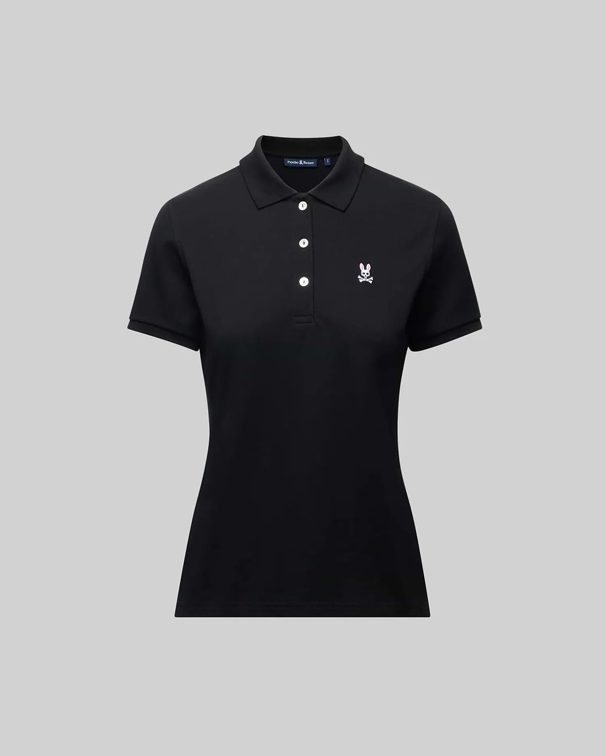 The Psycho Bunny WOMENS PIQUE POLO - WT0100003 is a black short-sleeve women's polo with a collar, three white buttons, and a small 4k-stitch embroidered Bunny logo on the left chest, shown on a plain gray background.