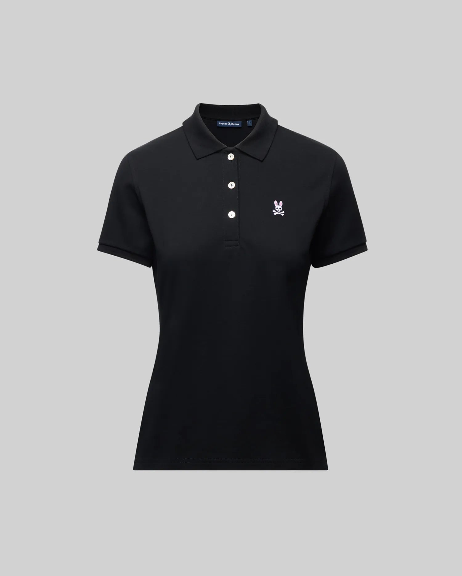 The Psycho Bunny WOMENS PIQUE POLO - WT0100003 is a black short-sleeve women's polo with a collar, three white buttons, and a small 4k-stitch embroidered Bunny logo on the left chest, shown on a plain gray background.