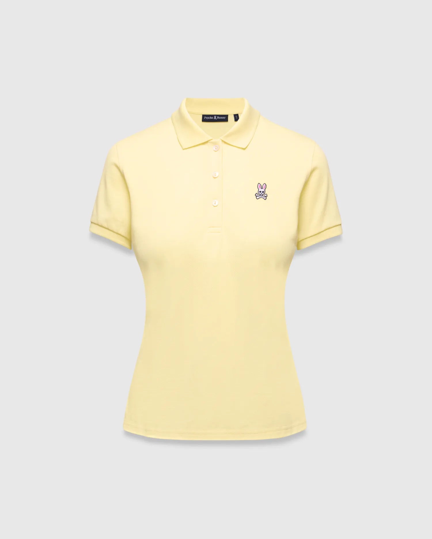 Women's Classic Pique Polo in pale yellow, featuring a classic fit, pique knit fabric, and a small embroidered pink and purple Psycho Bunny skull logo on the left chest.