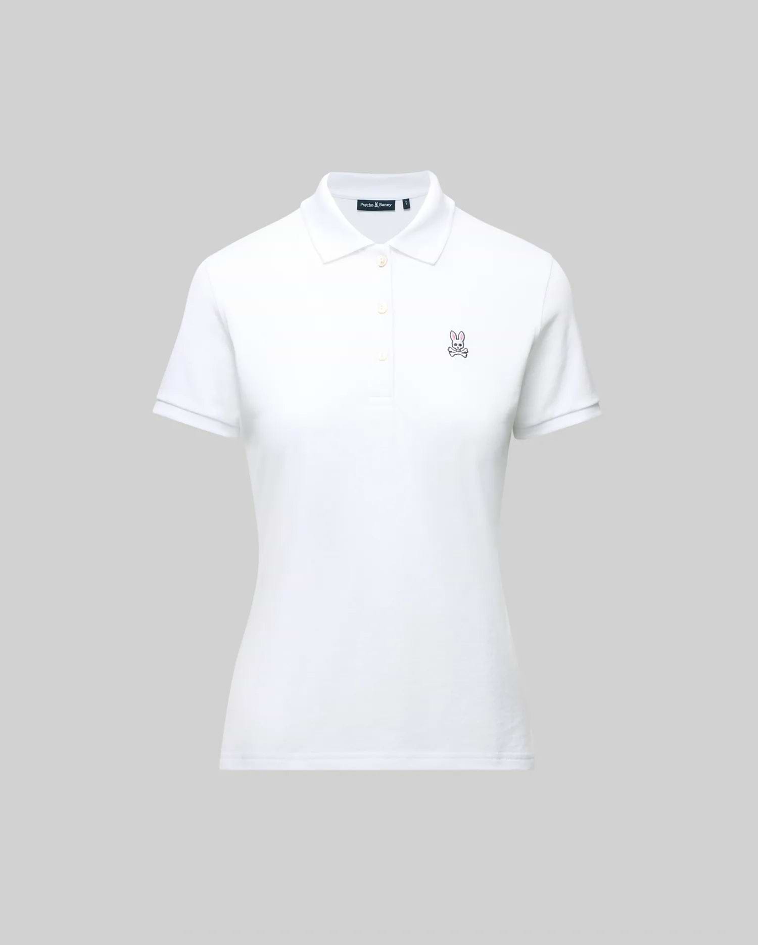 The WOMENS PIQUE POLO - WT0100003 by Psycho Bunny is a white short-sleeve polo featuring a collar, button placket, and 4k-stitch embroidered Bunny logo on the left chest, shown on a plain gray background.