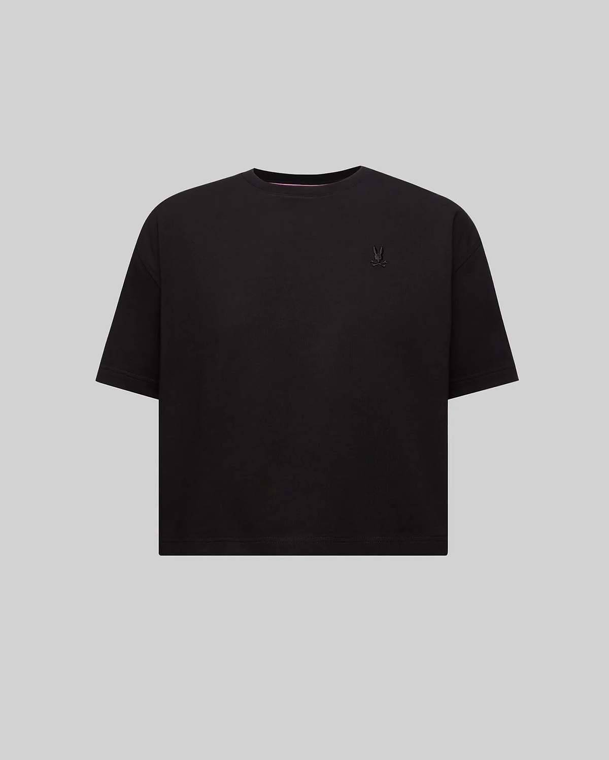 Women's Camille Oversized Fit Tee, a black oversized jersey knit t-shirt featuring a small embroidered black Psycho Bunny skull logo on the left chest and pink neck tape.