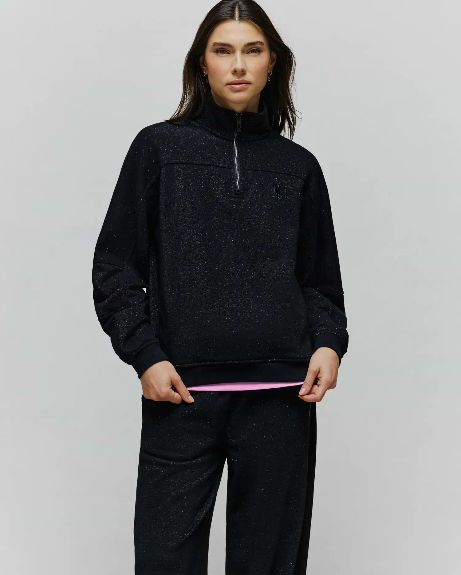 Womens Jules Lurex 1/4 Zip Pullover in black lurex knit with subtle silver sparkle, featuring a relaxed fit, high collar, 1/4 zip, and small embroidered black Psycho Bunny skull logo on the left chest.