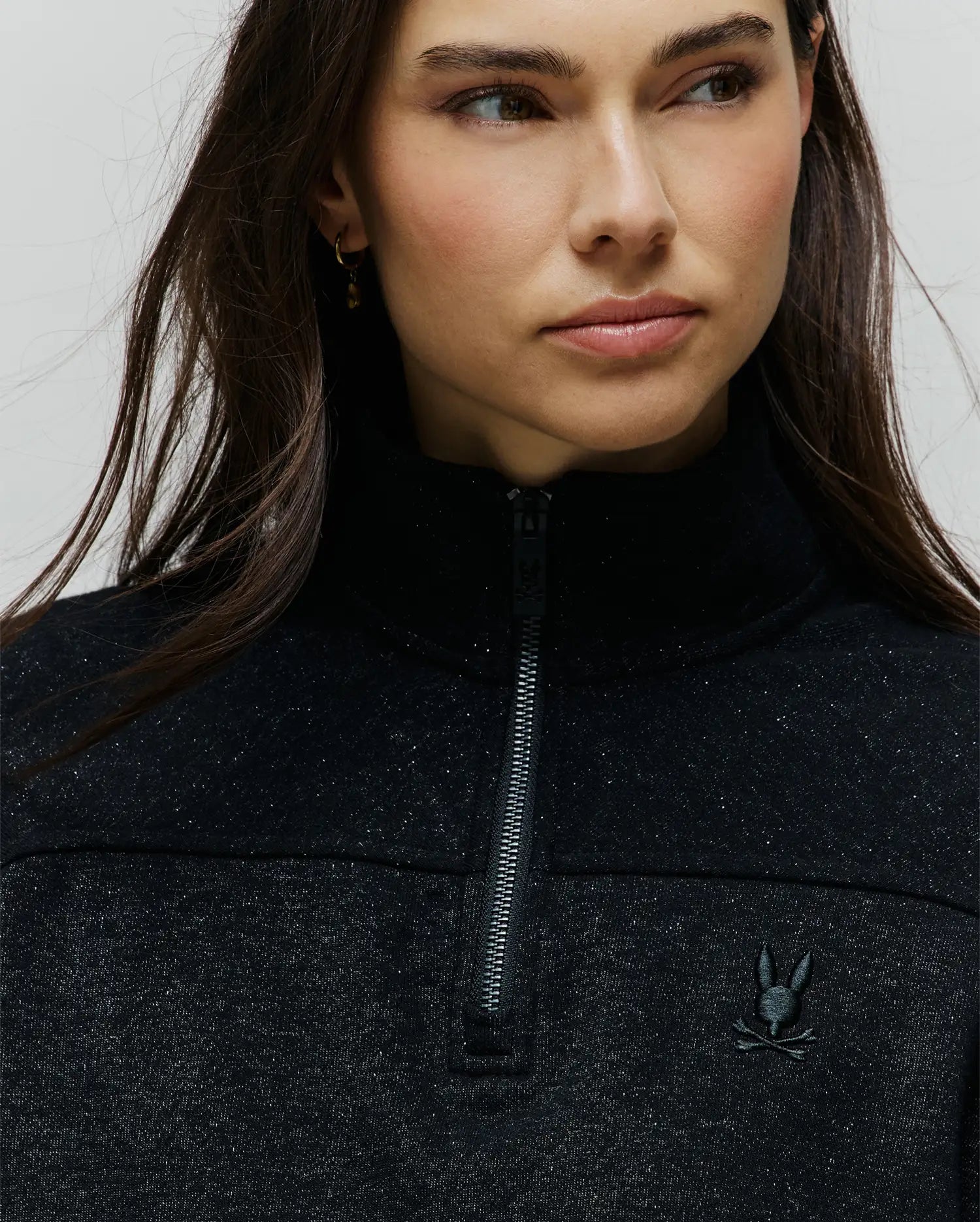Womens Jules Lurex 1/4 Zip Pullover, a classic fit black lurex knit with silver sparkle, featuring a high collar, 1/4 zip front, and a small embroidered black Psycho Bunny skull logo on the left chest.