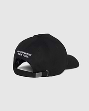 Back view of the men's Kingwood embroidered baseball cap (B6A916Y1HT) by Psycho Bunny in black, featuring white embroidered text that reads "PSYCHO BUNNY NEW YORK" above the adjustable backstrap. The cap has a metal buckle on the strap for size adjustment. Plain grey background.