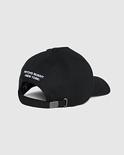 Back view of the men's Kingwood embroidered baseball cap (B6A916Y1HT) by Psycho Bunny in black, featuring white embroidered text that reads "PSYCHO BUNNY NEW YORK" above the adjustable backstrap. The cap has a metal buckle on the strap for size adjustment. Plain grey background.