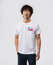 A young man with curly hair wearing a white MENS TEXAS TEE - B6U553W1PC shirt with a "Psycho Bunny" logo on the chest, paired with dark pants, standing against a plain background.