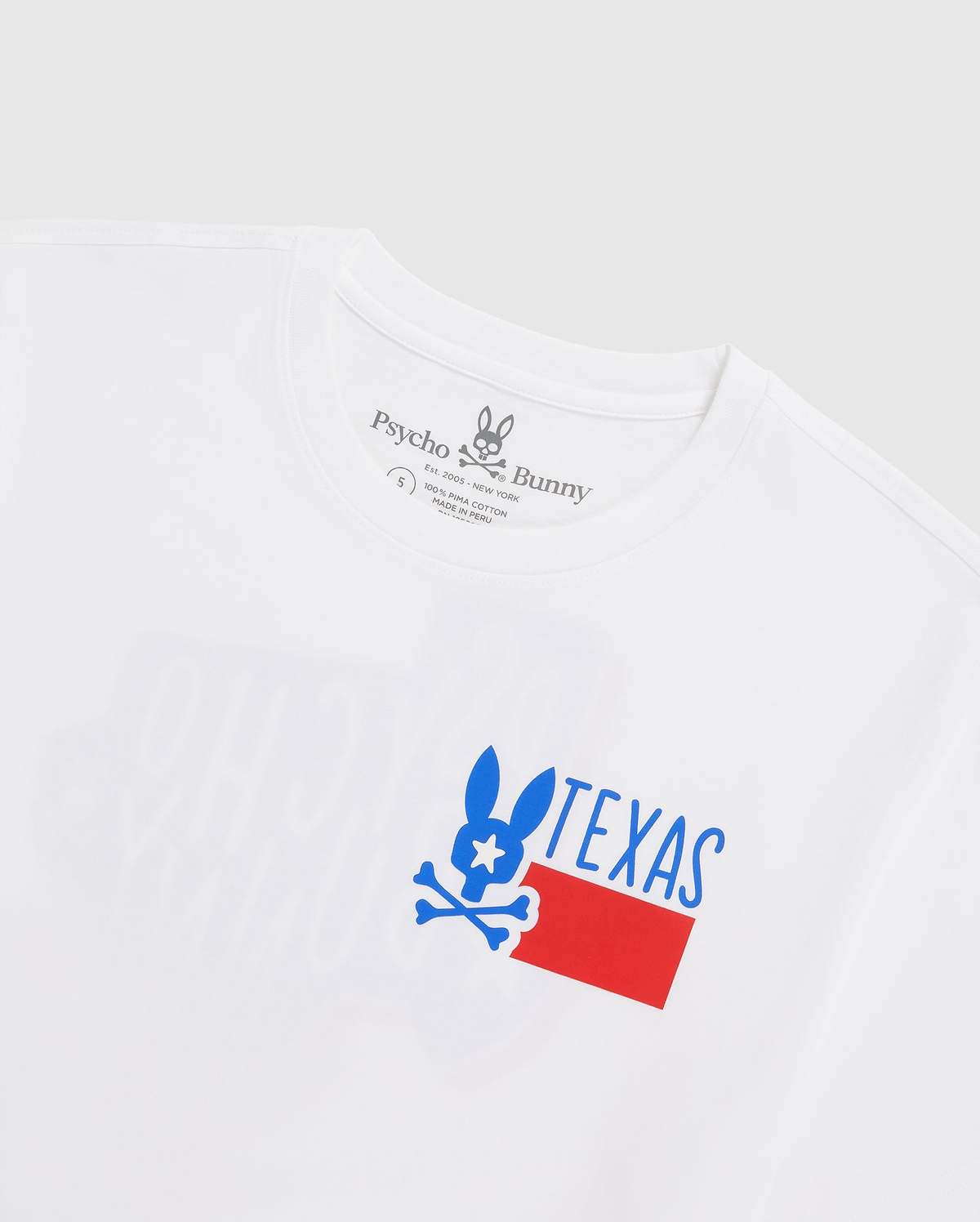 A close-up image of a white Pima cotton jersey MENS TEXAS TEE - B6U553W1PC featuring a Bunny logo graphic with a stylized rabbit above the word "TEXAS" with a design incorporating blue, white, and red colors by Psycho Bunny.