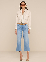 A woman stands against a white background, wearing the Micah Oversized Leather Jacket in beige with a cropped silhouette, paired with light blue cropped jeans, tan heels, sunglasses, and a brown belt featuring a small purse attachment.