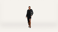 Woman in a black dress with a thigh-high slit, black leather jacket, and black heels stands confidently against a plain white background.