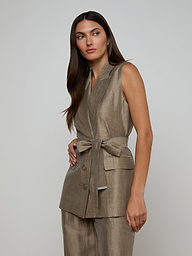 A woman with long dark hair wears the Harper Linen-Blend Vest with a tie belt and matching pants, standing against a plain off-white background and looking slightly to the side.