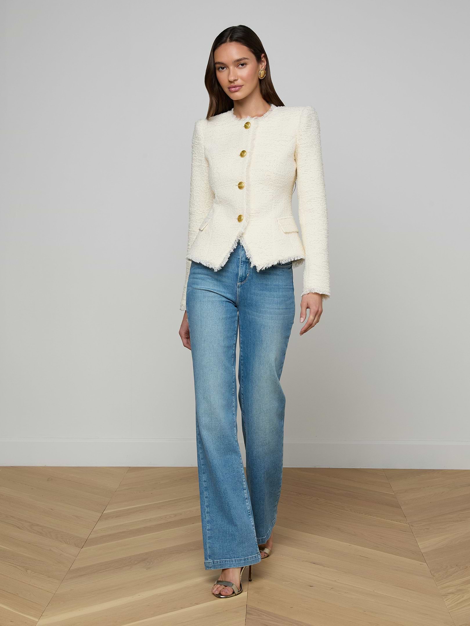 A woman wearing the Nerina Tweed Blazer, styled with blue wide-leg jeans and black heels, stands against a plain white background.