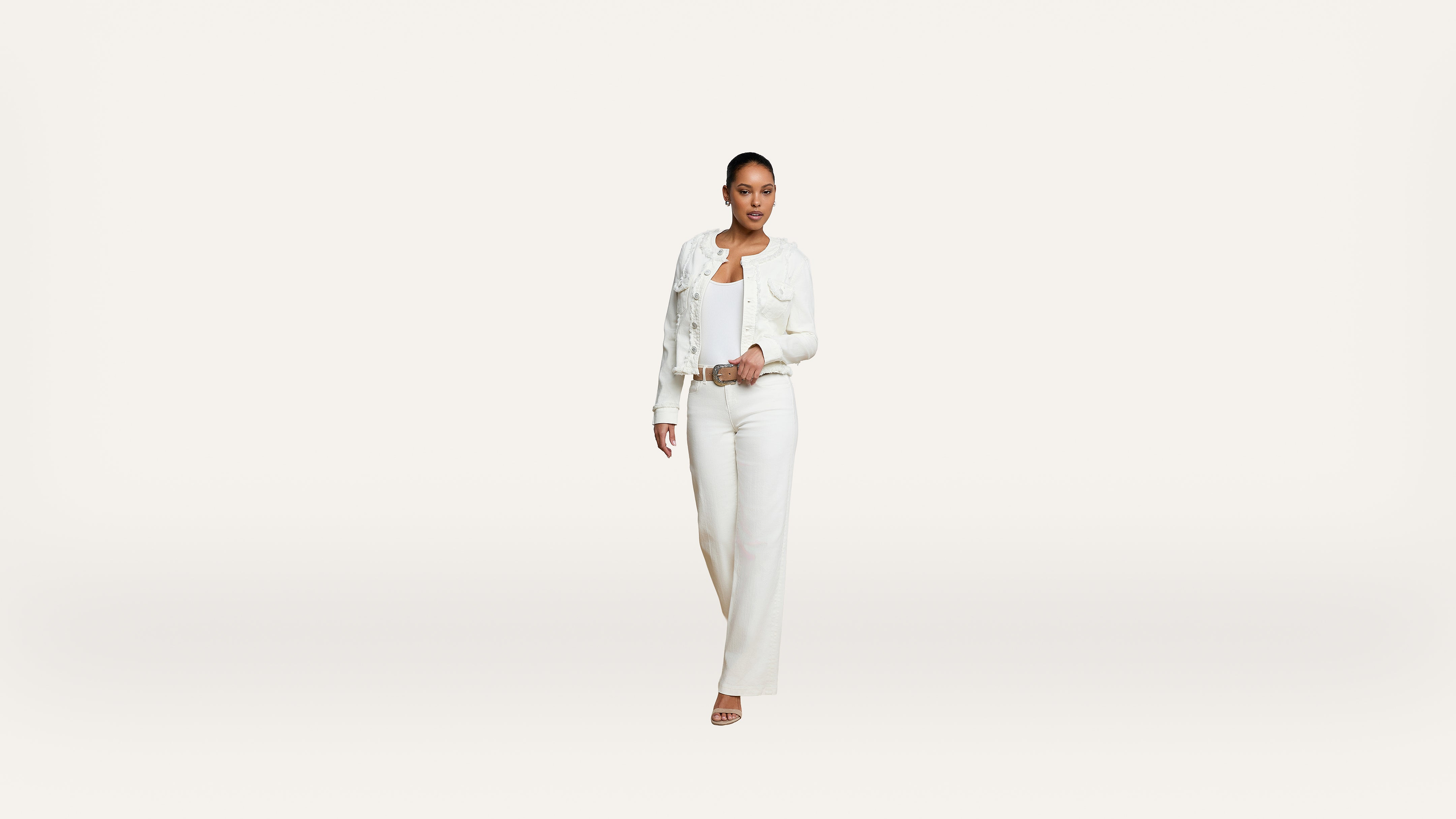 A person wearing a white jacket, white top, and white pants walks forward against a plain white background.