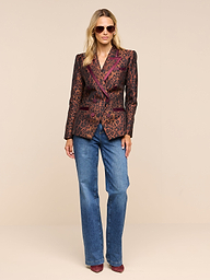 A woman wearing sunglasses, blue jeans, pointed shoes, and the Kyomi Double-Breasted Blazer stands against a plain white background.