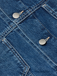 Close-up of the Silas Cape Jacket in blue all-cotton denim, featuring double seams and two metallic buttons that highlight the textured fabric and precise stitching details typical of this jean shirt jacket.