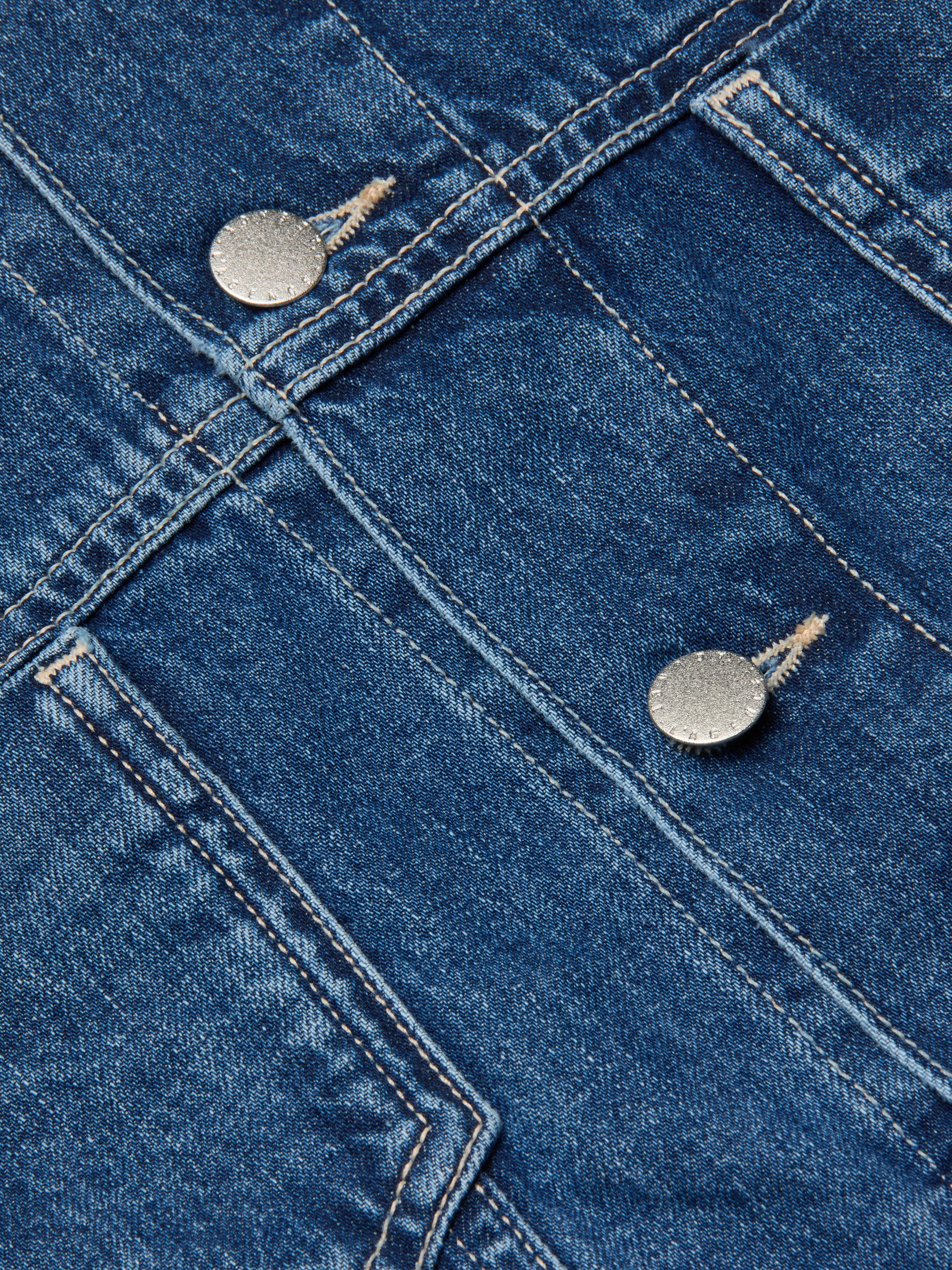 Close-up of the Silas Cape Jacket in blue all-cotton denim, featuring double seams and two metallic buttons that highlight the textured fabric and precise stitching details typical of this jean shirt jacket.