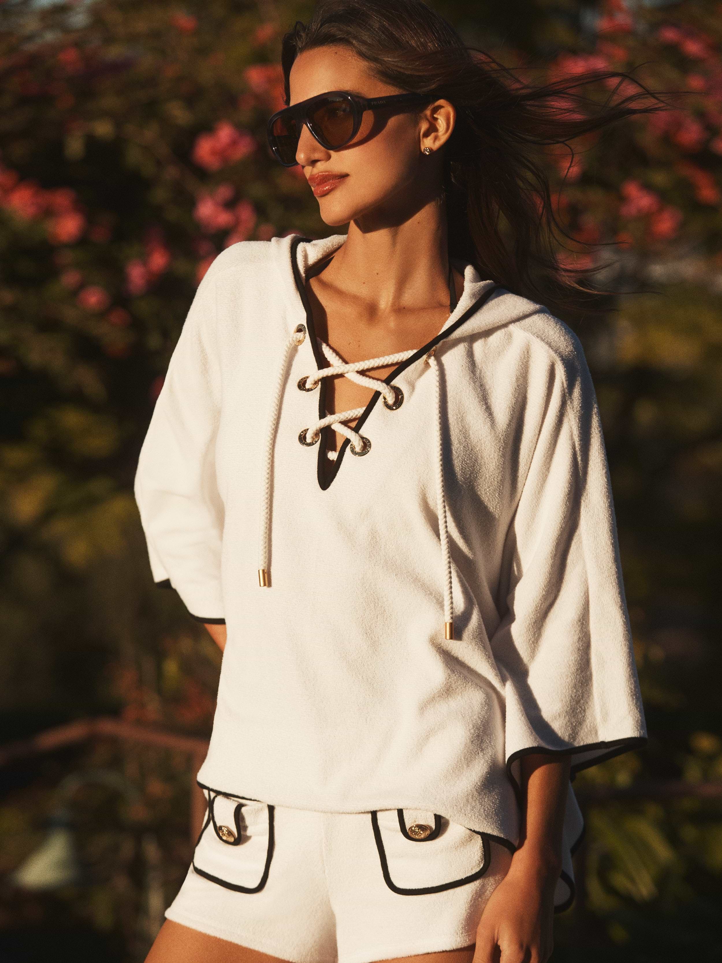 Woman wearing a white outfit with black accents in a natural setting
