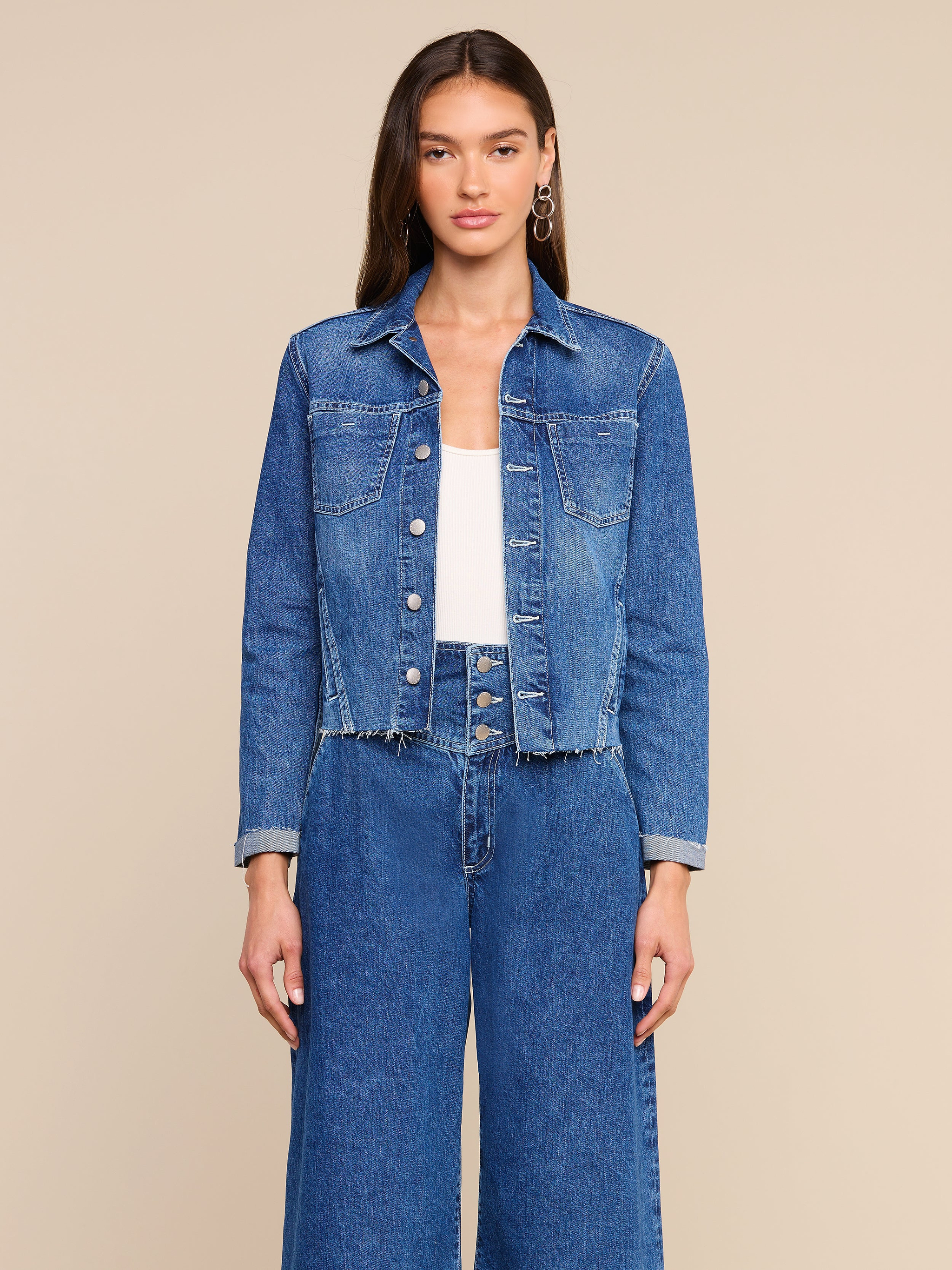 A woman wearing the Janelle Jean Jacket with a frayed hem and wide-leg jeans stands against a plain light background, facing forward with a neutral expression.