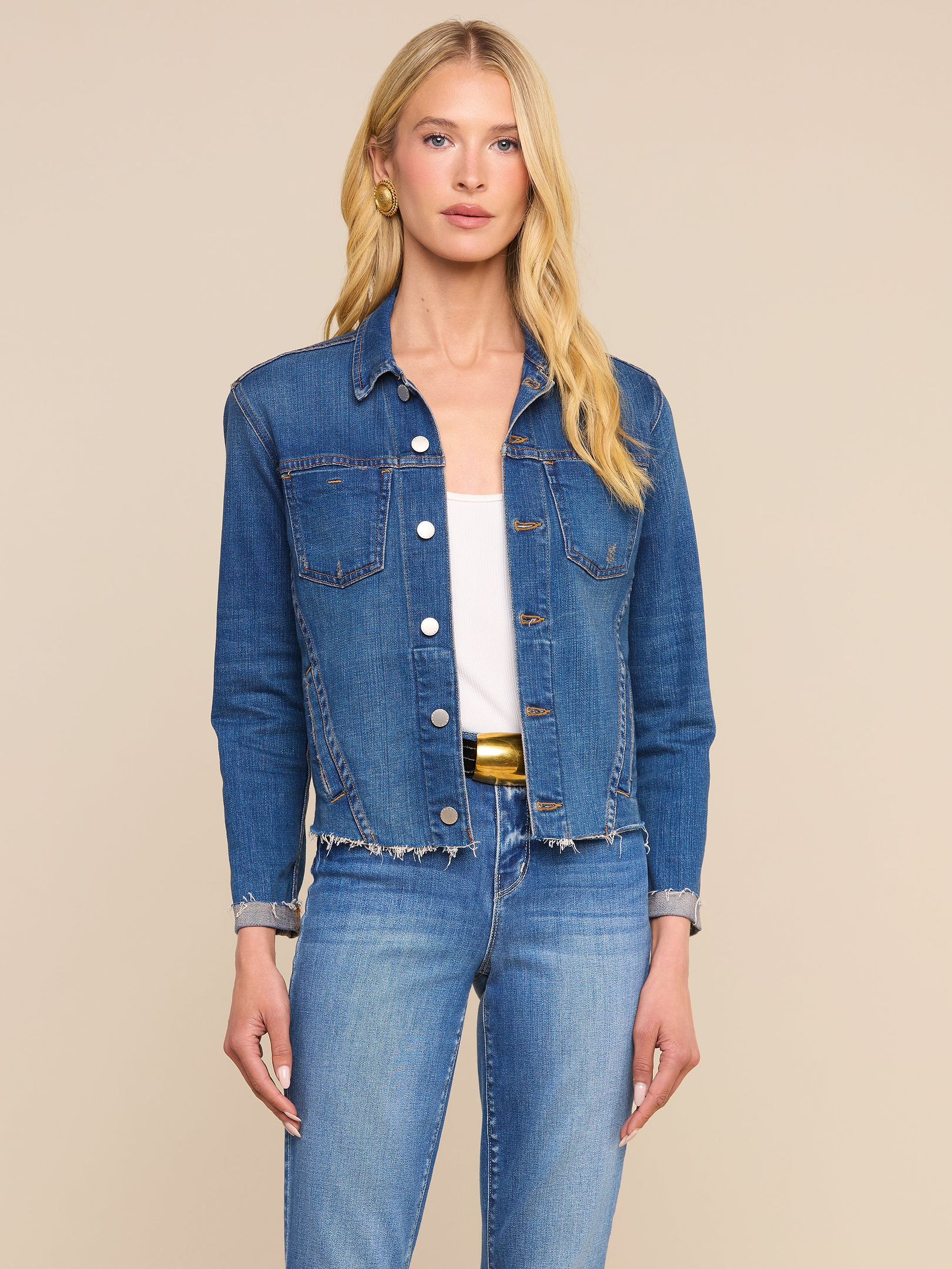 A woman with long blonde hair wears the Janelle Jean Jacket made from stretch denim, along with matching jeans, standing against a plain light background.