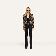 Woman wearing black sunglasses, the Jen Crystal Blazer—a couture-inspired, hand-embellished piece—paired with a black top, black flared pants, and black shoes stands against a plain white background.