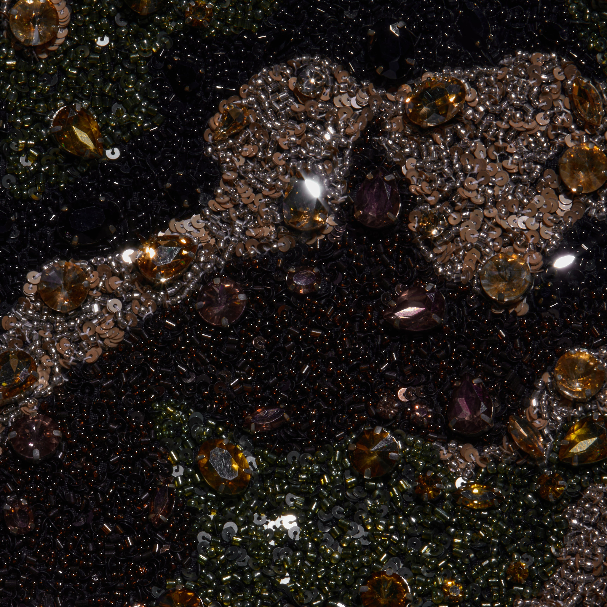 Close-up of the Jen Crystal Blazer’s couture-inspired embroidered fabric, embellished with sequins, shiny beads, and brown, gold, and dark gemstones arranged in an ornate abstract pattern.