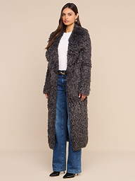 A woman stands against a white background wearing the Lizbeth Faux Fur Jacket—a long, gray, textured relaxed fit style—over a white top, blue jeans, and black shoes.