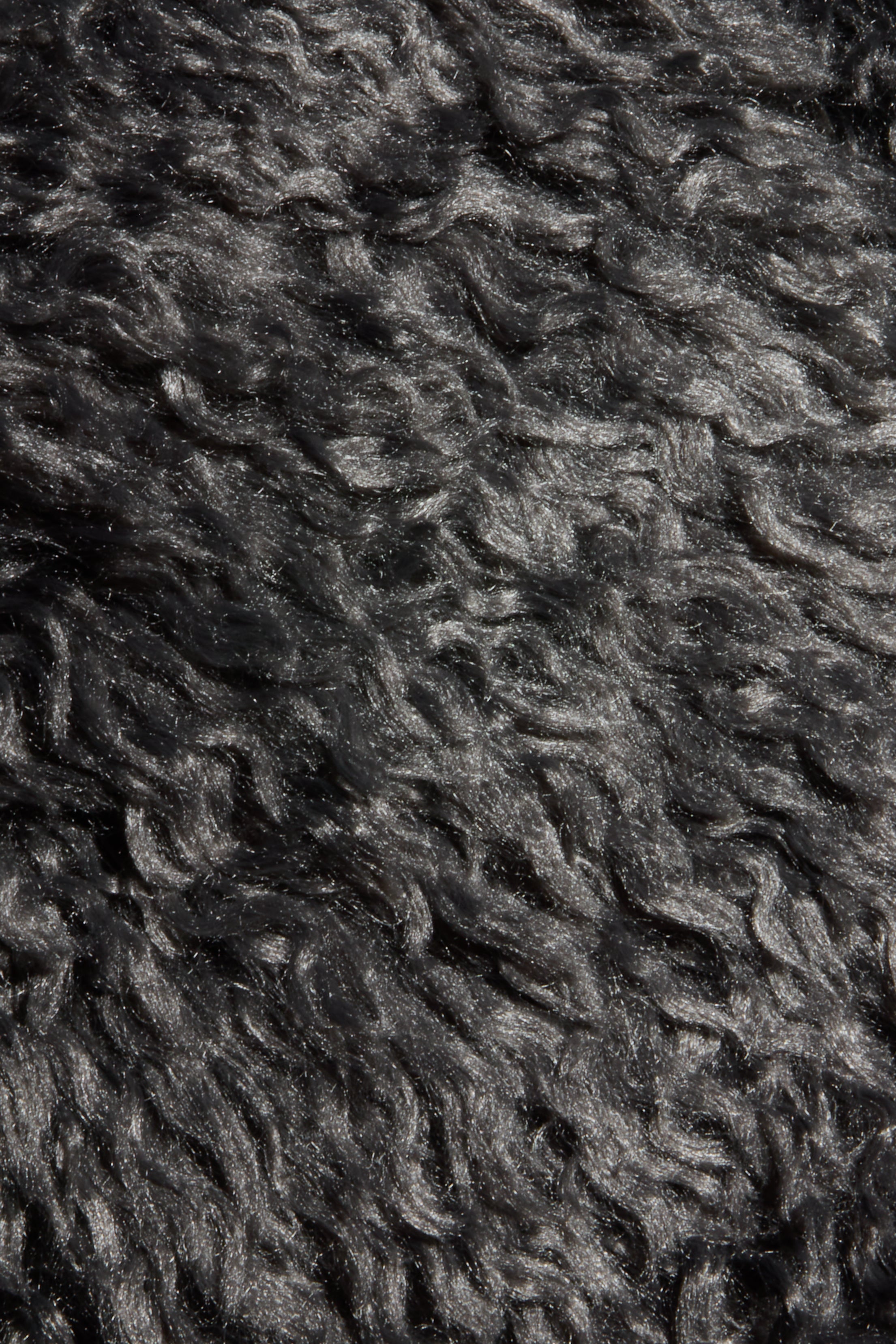 Close-up of the Lizbeth Faux Fur Jacket in dark gray, featuring curly, textured shag faux fur with wavy patterns and a lustrous surface that catches the light—evoking styles seen at New York Fashion Week.