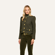 A woman wearing the Zell Tweed Jacket—a dark green, collarless tweed jacket with gold buttons—paired with an olive green turtleneck and matching corduroy pants, stands against a plain light background.